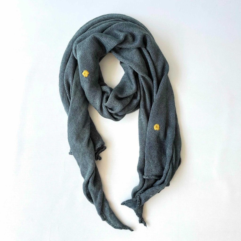 A hand dyed scarf is visibly mended to merge creativity with sustainability and longevity.