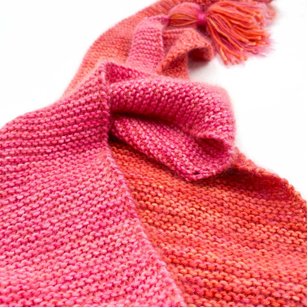 Close up of the Cowgirlblues Baktus Scarf knit in Merino DK Hot Pink and Carrot Juice, with the matching shades of Cowgirlblues Kidsilk.
